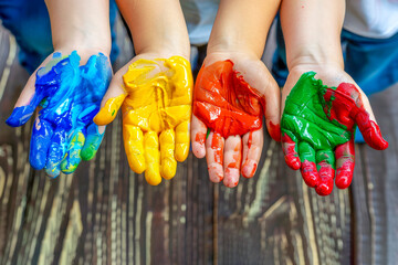Four children's hands, smeared with colorful paints. Symbolizing creativity, playfulness, joy, and the process of exploration and self-expression in children. Generative AI.