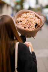 Young woman holding a large bouquet of peach roses