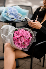 Focus on a large bouquet of pink roses on the lap of a young woman