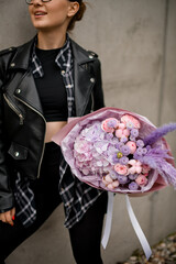 Young pretty woman holding a bouquet of purple hydrangeas with pink roses and other flowers