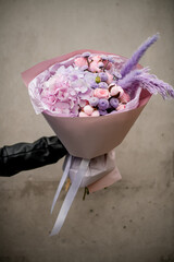 Female hand holding a bouquet of purple hydrangeas with pink roses and other flowers