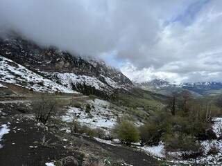 Tseylomsky pass in Ingushetia. A trip uphill to the Tsei Loam pass on a cloudy spring day. Panorama of the high cliffs of the Dzheyrakh gorge. North Caucasus, Russia