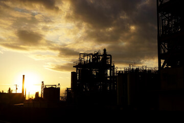 工業地帯に落ちる夕陽とプラントのシルエット
