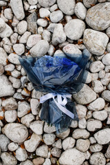 Bouquet of blue hydrangeas and blue roses rests on small stones