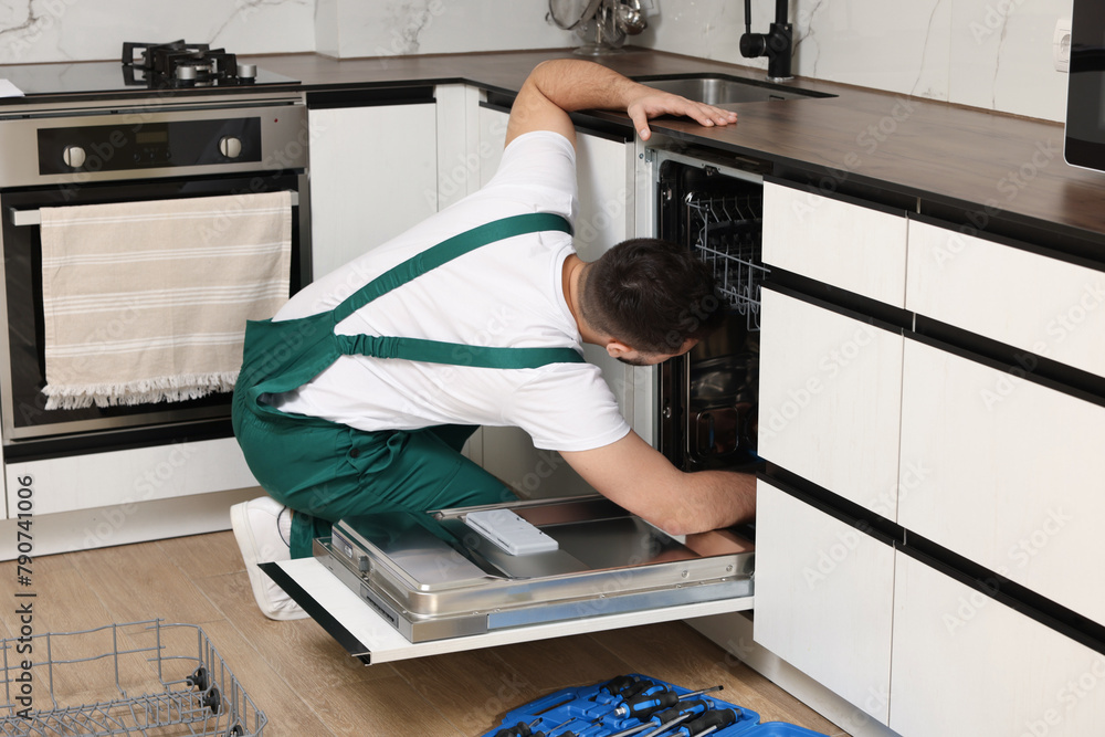 Canvas Prints serviceman repairing dishwasher near toolbox in kitchen