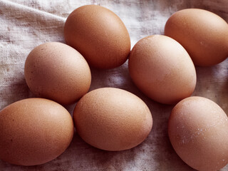 The image captures 7 brown eggs with visible speckles resting on an uneven fabric, conveying an organic feel.