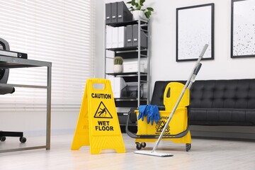 Cleaning service. Mop, wet floor sign and bucket with supplies in office