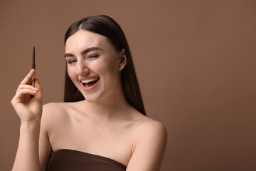 Fototapeta premium Happy woman with freckle pen on brown background. Space for text