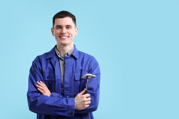 Professional repairman holding hammer on light blue background. Space for text