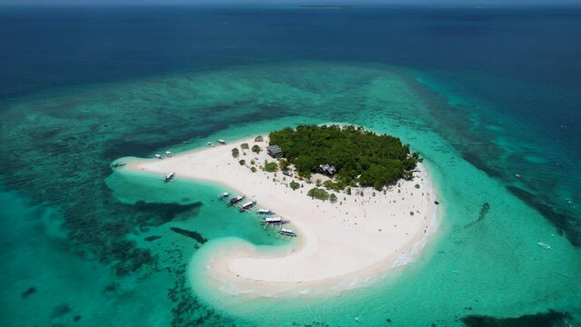 4K Aerial Drone video of Patawan Island with beautiful white sand and turquoise blue water. Boats anchored on the beach with palm trees in the middle. Balabac, Philippines