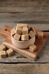 Brown sugar cubes in bowl on wooden table, closeup