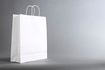 One white paper bag on grey background, space for text. Mockup for design