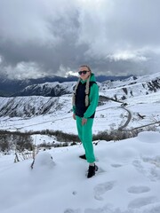 A woman on the background of the Ceylomsky pass in Ingushetia. A trip uphill to the Tsei Lum pass on a cloudy spring day. Panorama of the high cliffs of the Dzheyrakh gorge