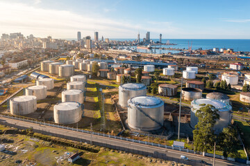 Aerial view of industrial oil and gas steel storage tanks of oil and LPG petrochemical. Oil tank farm for gas, diesel and petroleum in a sea port near industrial plant and chemical refinery