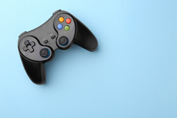 Wireless game controller on light blue background, top view. Space for text
