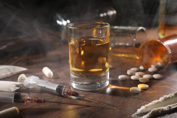 Alcohol and drug addiction. Whiskey in glass, syringes, pills and cocaine on wooden table