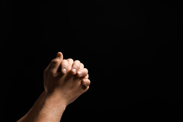 Religion. Christian man praying on black background, closeup. Space for text