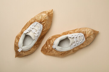 Sneakers in shoe covers on beige background, top view