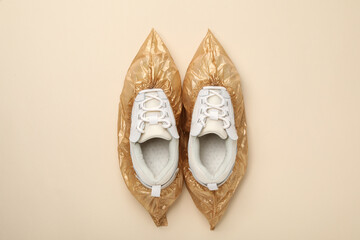 Sneakers in shoe covers on beige background, top view