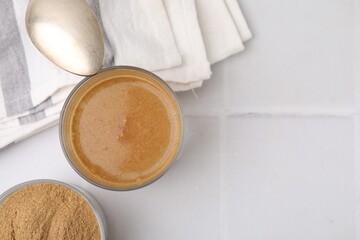 Soluble fiber with water in glass, powder and spoon on white tiled table, top view. Space for text