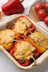 Delicious stuffed peppers in baking dish on white textured table