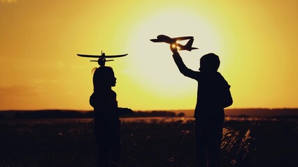Future pilot. Children boy play with toy airplane outdoor, Silhouette. Child pilot runs with toy...