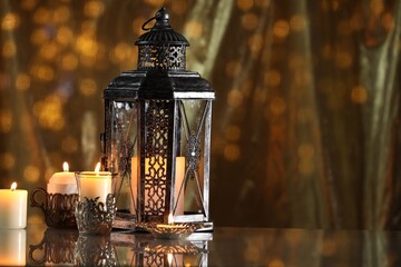Arabic lantern and burning candles on mirror surface against blurred lights, space for text