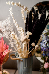 Craspedia dried flowers and other decorative sprigs of dried flowers stand in a tall vase