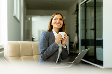 Professional woman enjoying a warm beverage during a break in her modern office space