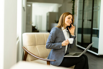 Elegant professional woman engaged in a business call with morning coffee