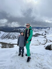 A woman with a child on the background of the Ceylomsky pass in Ingushetia. A trip uphill to the...