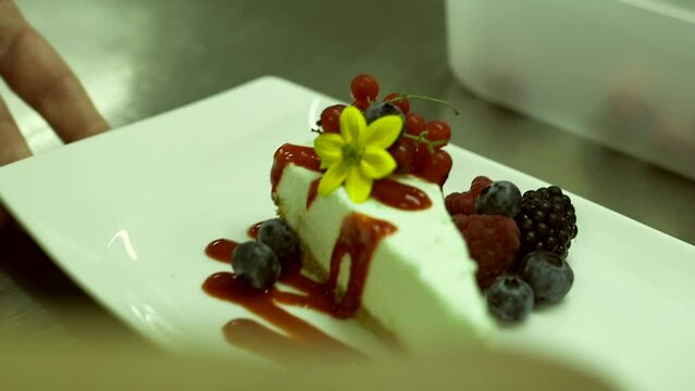 Chef Adds Yellow Flower to a Beautifully Decorated Cheesecake with Wild Berries. Cheesecake is a Dessert Made with a Soft Fresh Cheese, Typically Cottage, Cream Quark Cheese, Ricotta, eggs, and sugar.