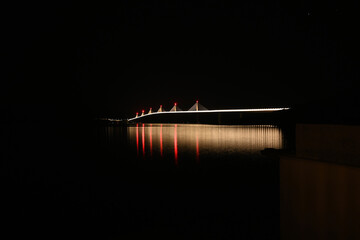 Illuminated bridge over the sea at night. A large white suspension bridge over the water. Peljesac bridge, Croatia. 