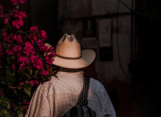 Naklejka premium Mexican Man in White Hat Standing Near Bright Pink Flowers in San Miguel de Allende, Mexico