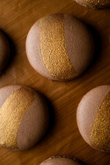 Close-up top view of several macaroon halves with lines drawn with gold food coloring
