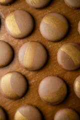 Freshly baked halves of brown macaroons with golden stripes