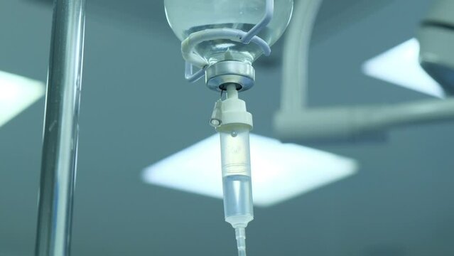 Detail close-up of vitamin IV drip chamber dripping on medical clinic. Dripping for intravenous infusion during surgery.