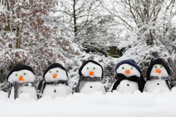 Five adorable snowmen in a row outdoors Christmas time dressed in winter clothing of hats and scarfs - 790752097