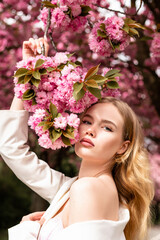 Naklejka premium Close-up portrait of a young attractive woman with cherry blossoms. Sunny day