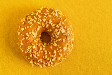 caramel glazed donut on yellow surface close up top view