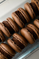 Cropped close-up photo of brown macaroons smeared with chocolate cream