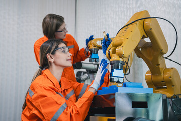 Engineering student assembling a robotic arm using a computer in a technology workshop. Service engineer holding a robot controller and inspecting the robotic arm's welding hardware.