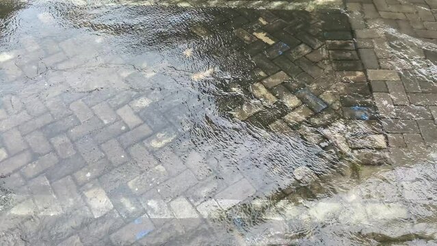Top view or flat lay view of shallow water flow on grey paved background, flood on the street