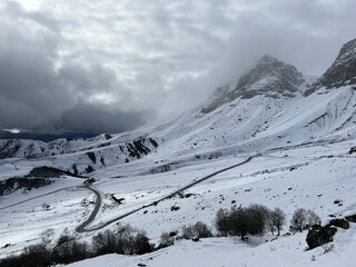 Tseylomsky pass in Ingushetia. A trip uphill to the Tsei Loam pass on a cloudy spring day. Panorama of the high cliffs of the Dzheyrakh gorge. North Caucasus, Russia