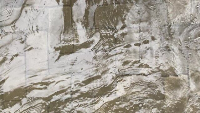 Top view or flat lay view of shallow water flow on grey paved background, flood on the street