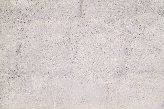 grayish white wall of coated chuff bricks with a sanded texture