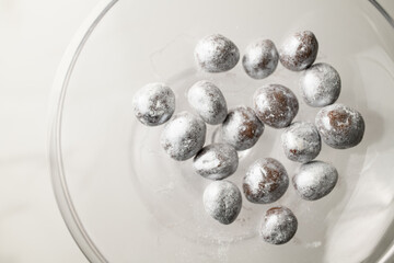 Nuts sprinkled with silver paint lie in a glass transparent round bowl