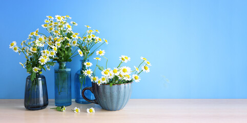 spring bouquet of daisies flowers over wooden table and blue background - 790766434