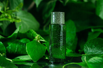 Green small bottle on a green background. Serum, vitamins, water