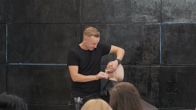 Hairdresser creating a clean line on a blonde bob cut